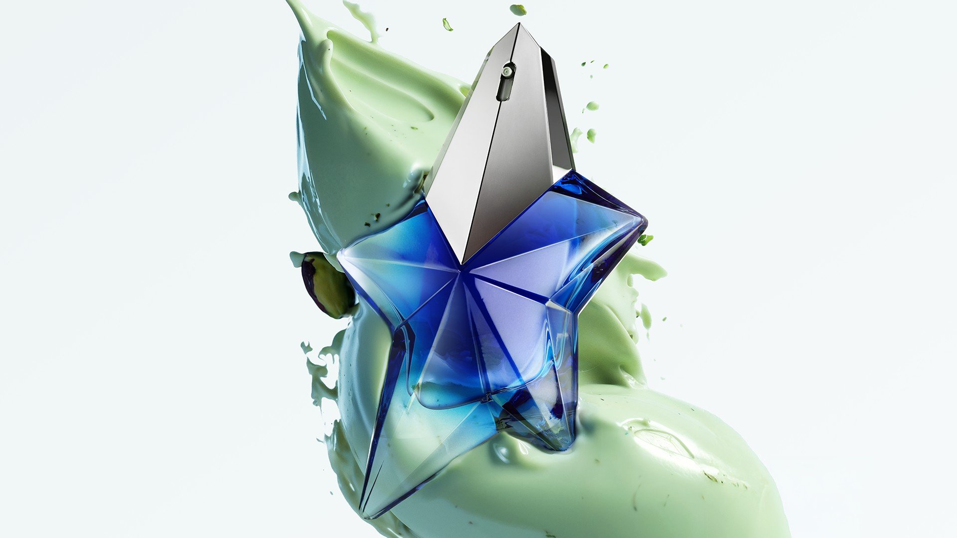 Angel Stellar Eau de Parfum bottle, against a backdrop of creamy, light green pistachio, highlighting one of its key ingredients