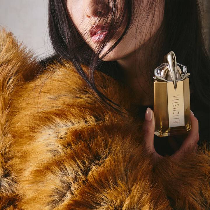 Model holding a bottle of Alien Goddess Eau de Parfum close to the skin.