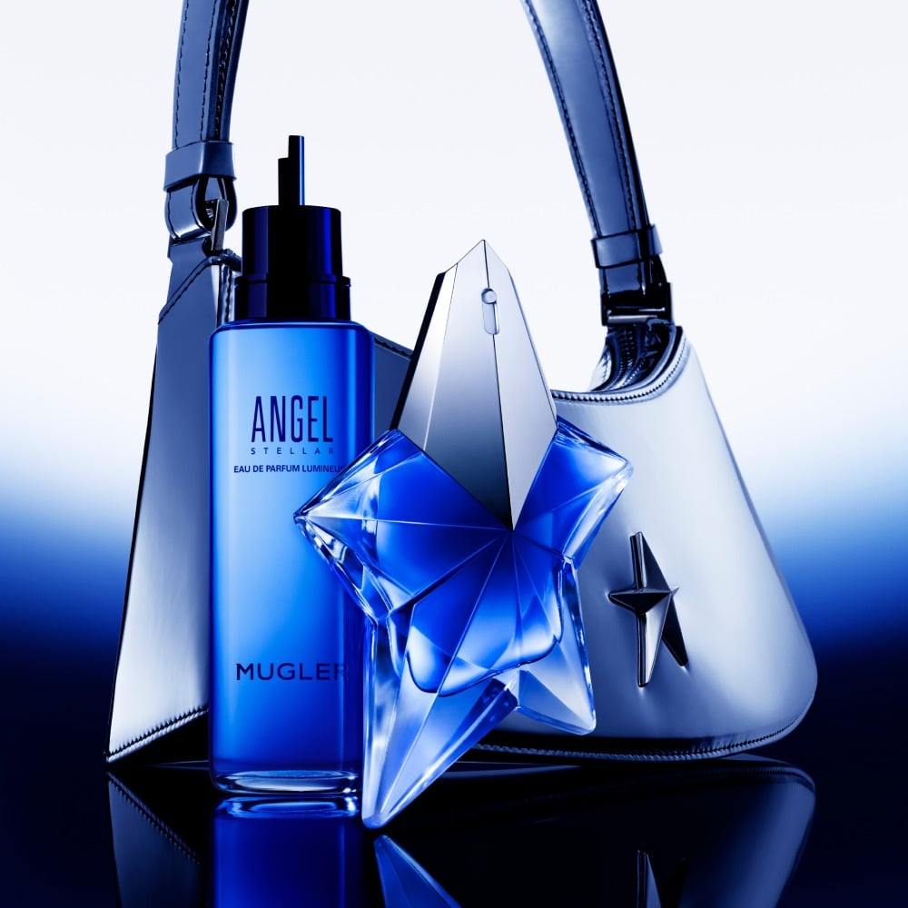 Angel Stellar Eau de Parfum bottle, against a backdrop of creamy, light green pistachio, highlighting one of its key ingredients
