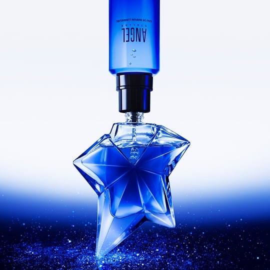 Angel Stellar Eau de Parfum bottle, against a backdrop of creamy, light green pistachio, highlighting one of its key ingredients
